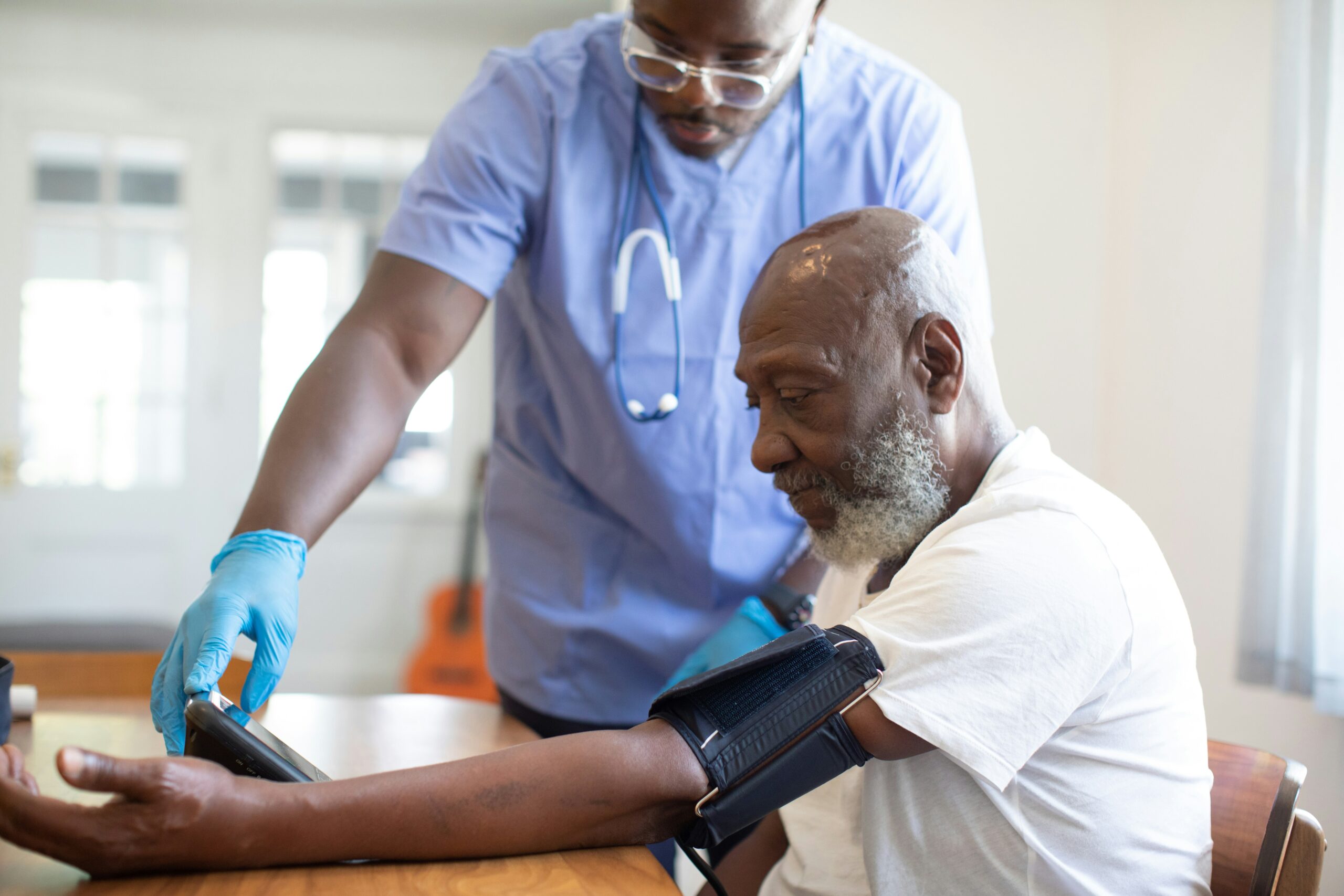 A clinician measures an older man's blood pressure during an annual wellness visit at a family medicine clinic.